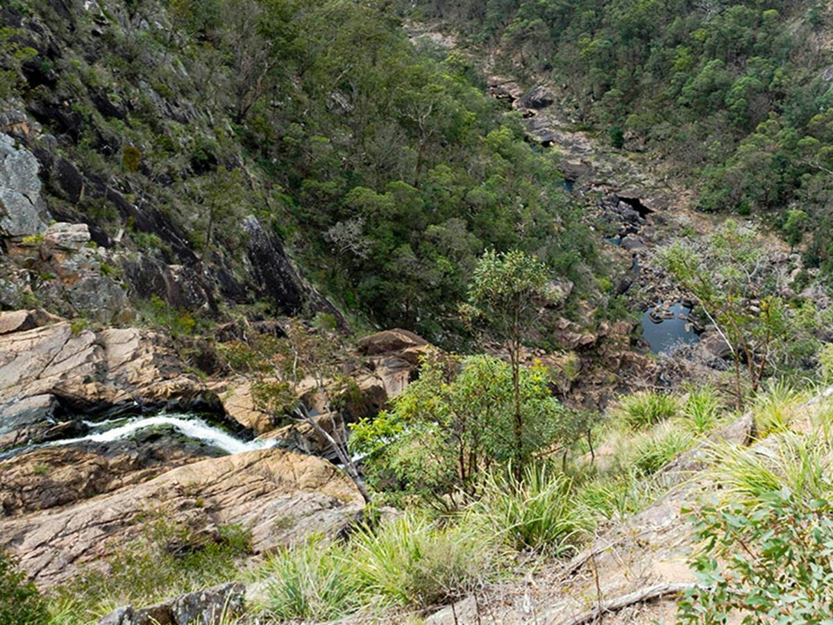 View of Boonoo Boonoo Falls plummeting over rock ledges into a steep rocky valley. Photo credit: