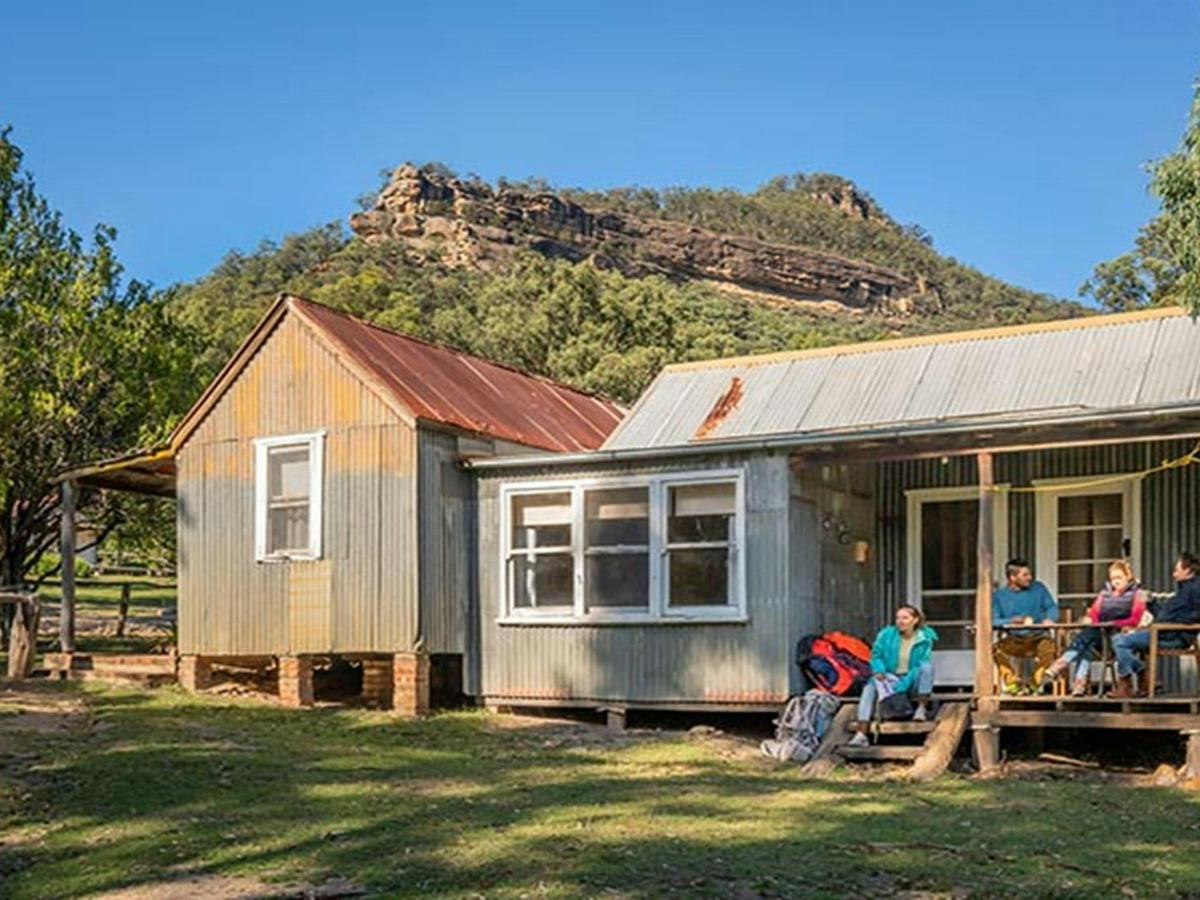 A group of friends relaxing on the verandah of Slippery Norris Cottage in Yerranderie Regional Park.