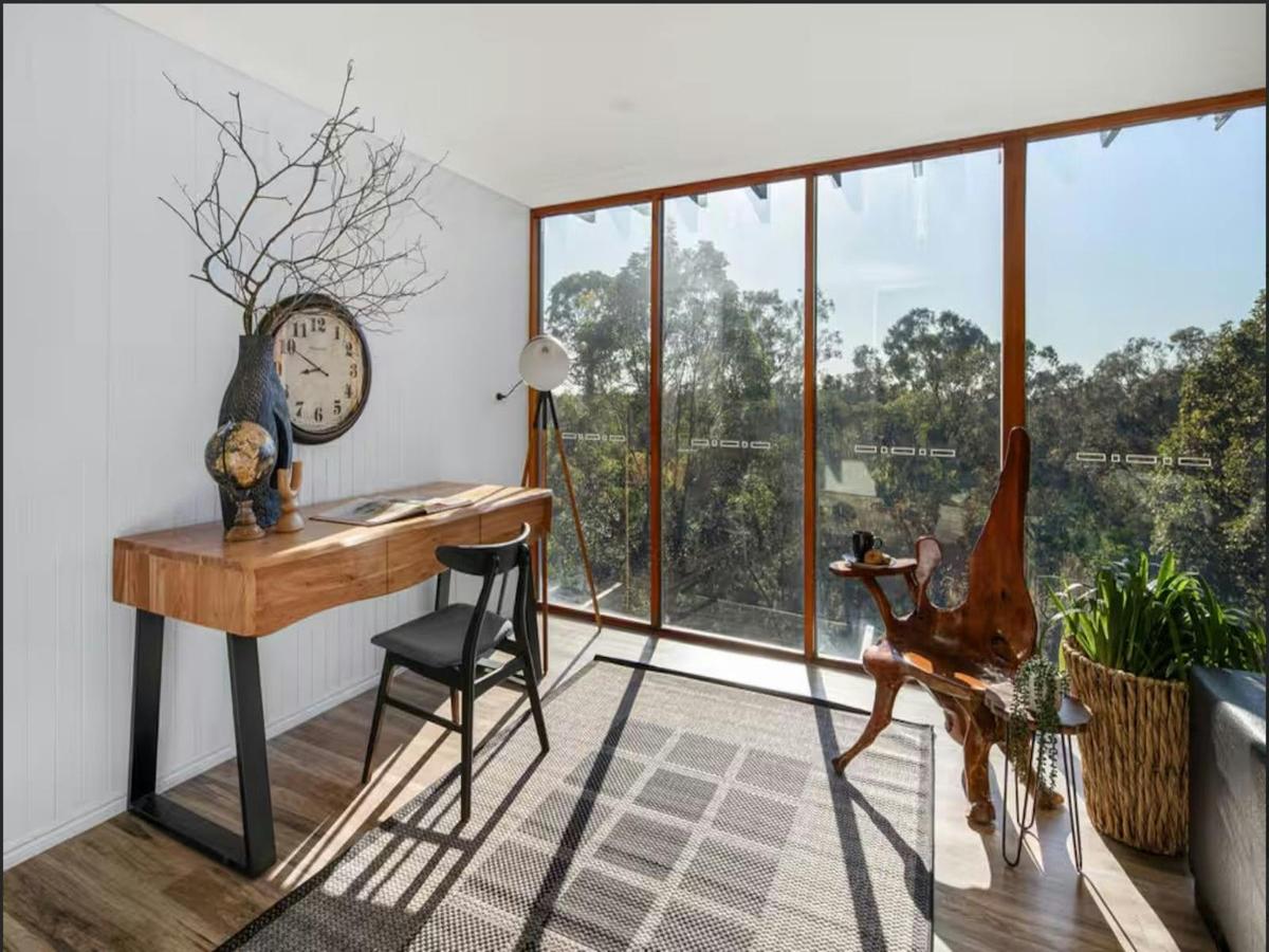 Lush greenery and natural light flood this tranquil home office, offering a stunning view to inspire