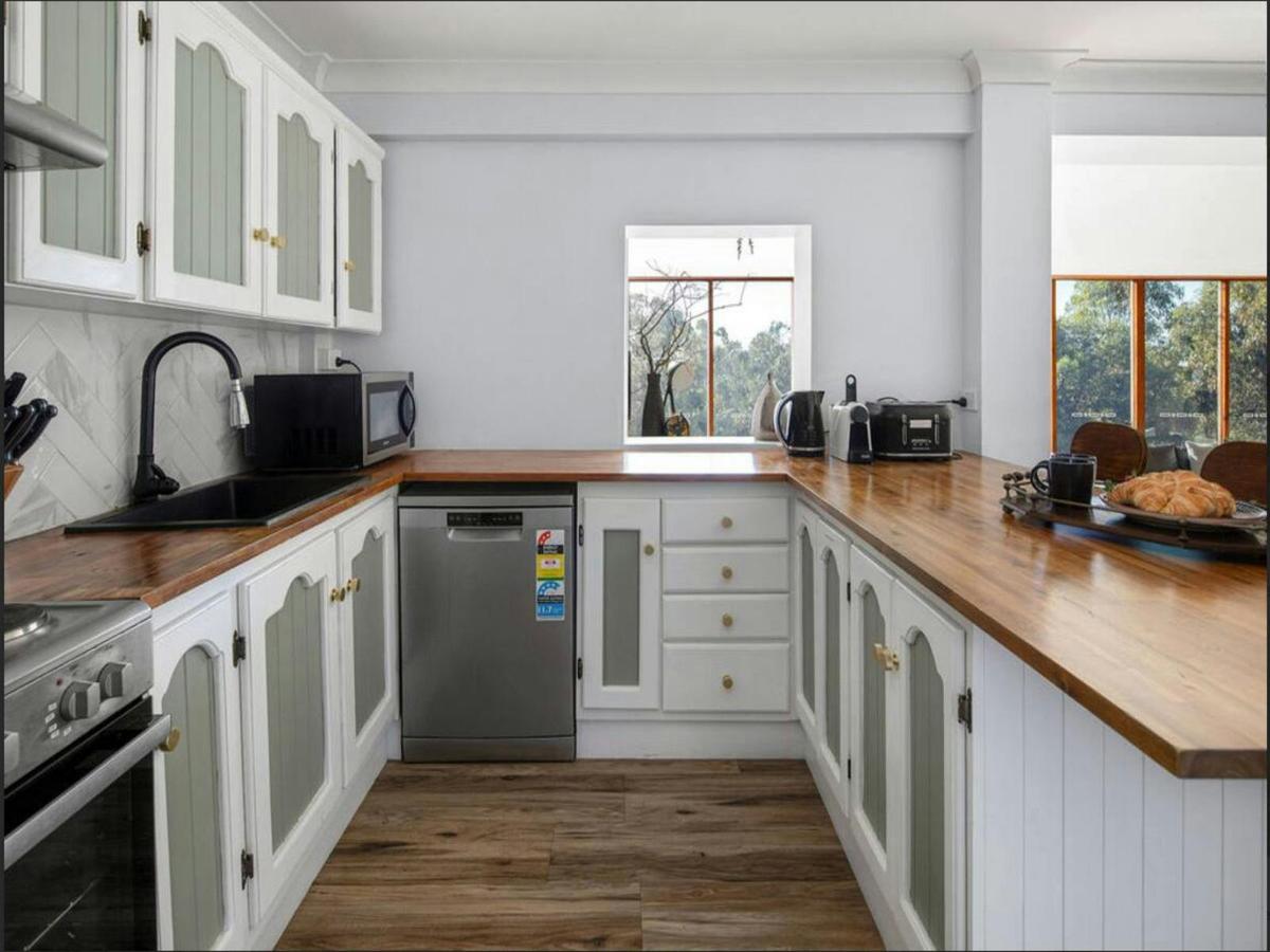 A bright and airy kitchen with wood countertops and a view of the surrounding landscape.