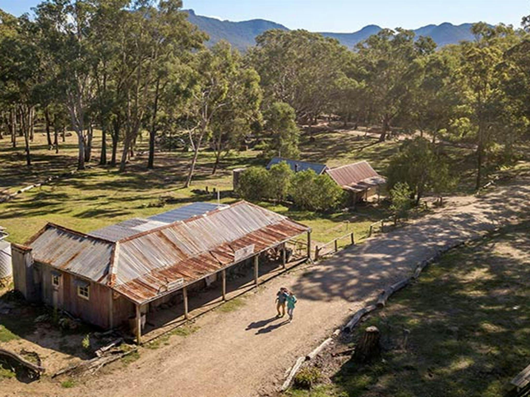 Two people walking from The Bank Room down the main street of Yerranderie Private Town, in