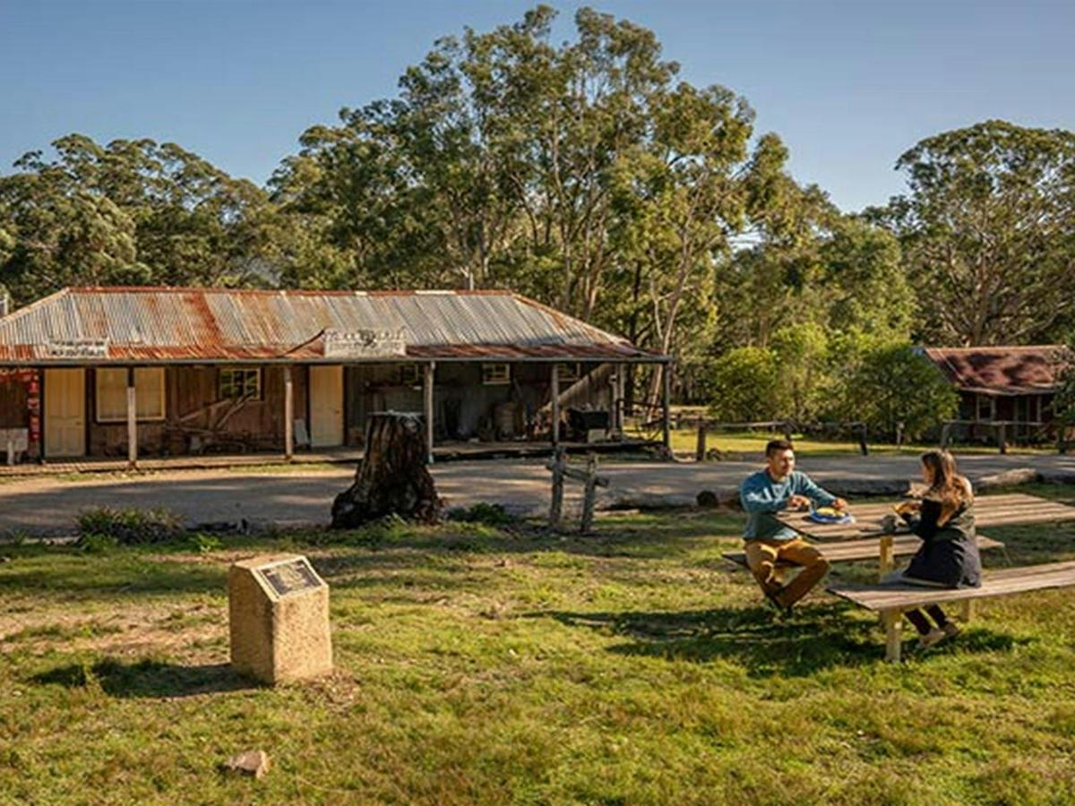 A couple enjoying morning tea at the picnic table outside The Bank Room in Yerranderie Regional Park