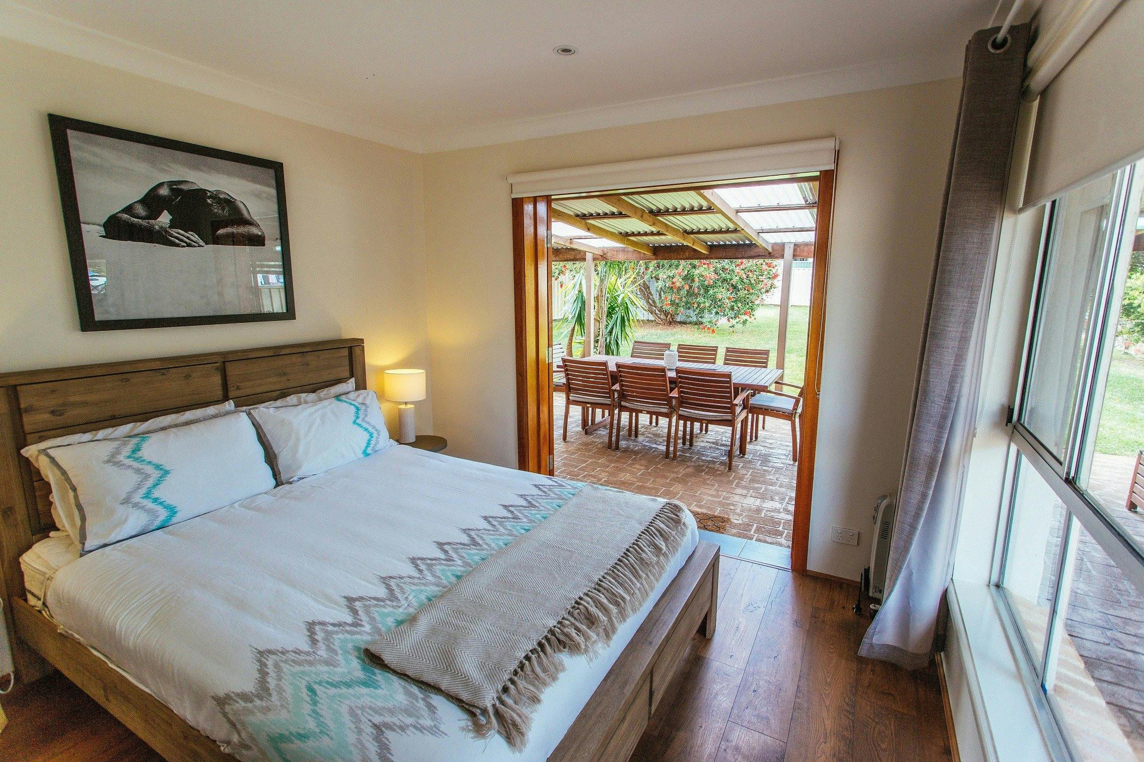 Queen bedroom with doors opening onto patio and lovely garderns.
