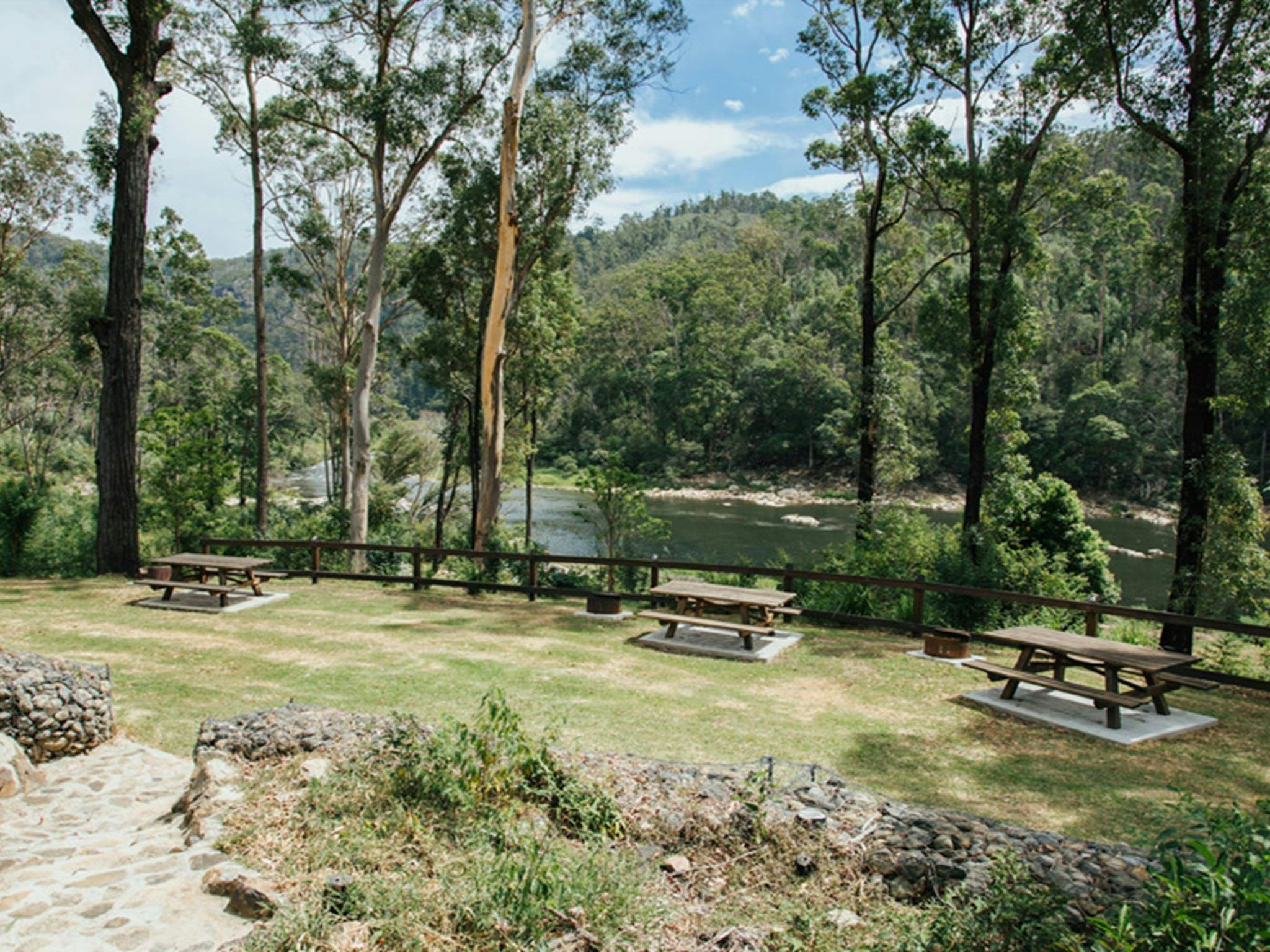 Camping area with picnic tables by Nymboida River at The Junction campground at Nymboi-Binderay