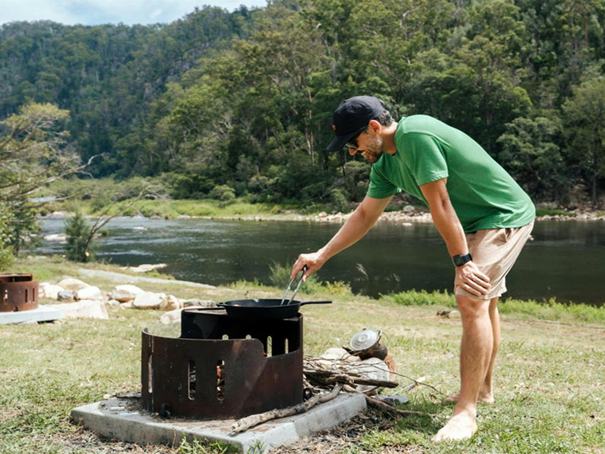 Person cooking on a fire pit at The Junction campground by Nymboida River, Nymboi-Binderay National