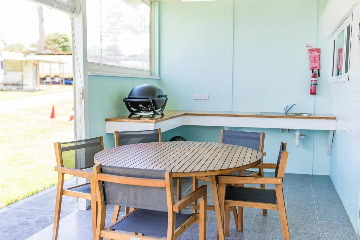 Surfside Caravan 2 exterior kitchen with Weber Q and outdoor table setting for five