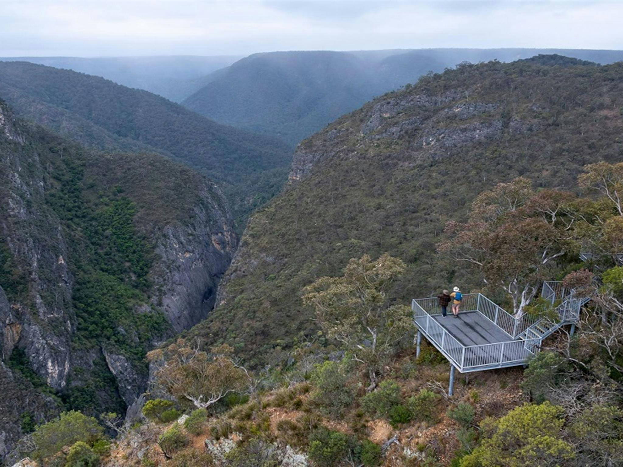 Aerial view of Adams lookout, with 2 people admiring the view over dramatic gorges, Bungonia