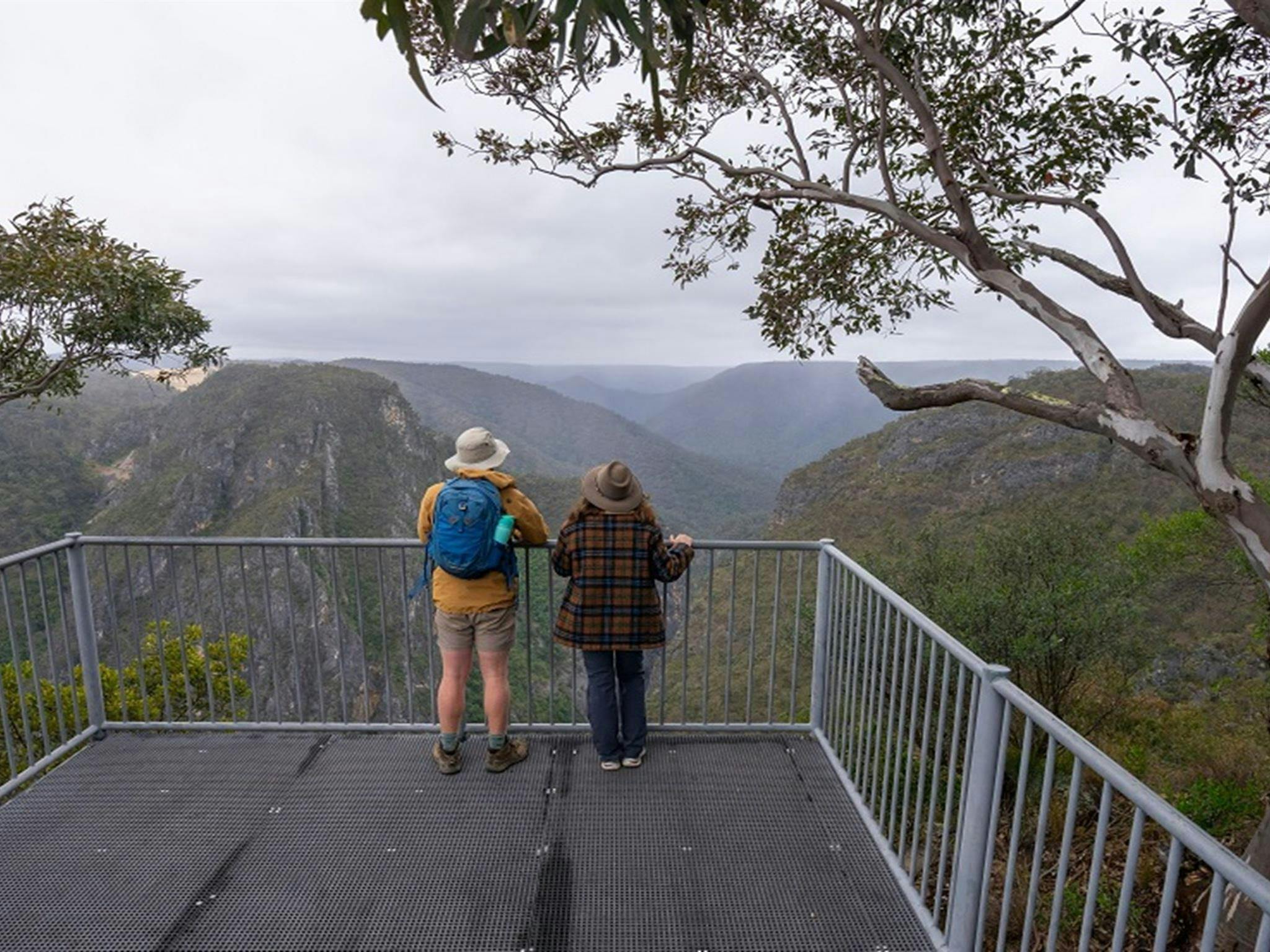 Two people admiring the view of surrounding mountains from Adams lookout, Bungonia National Park.