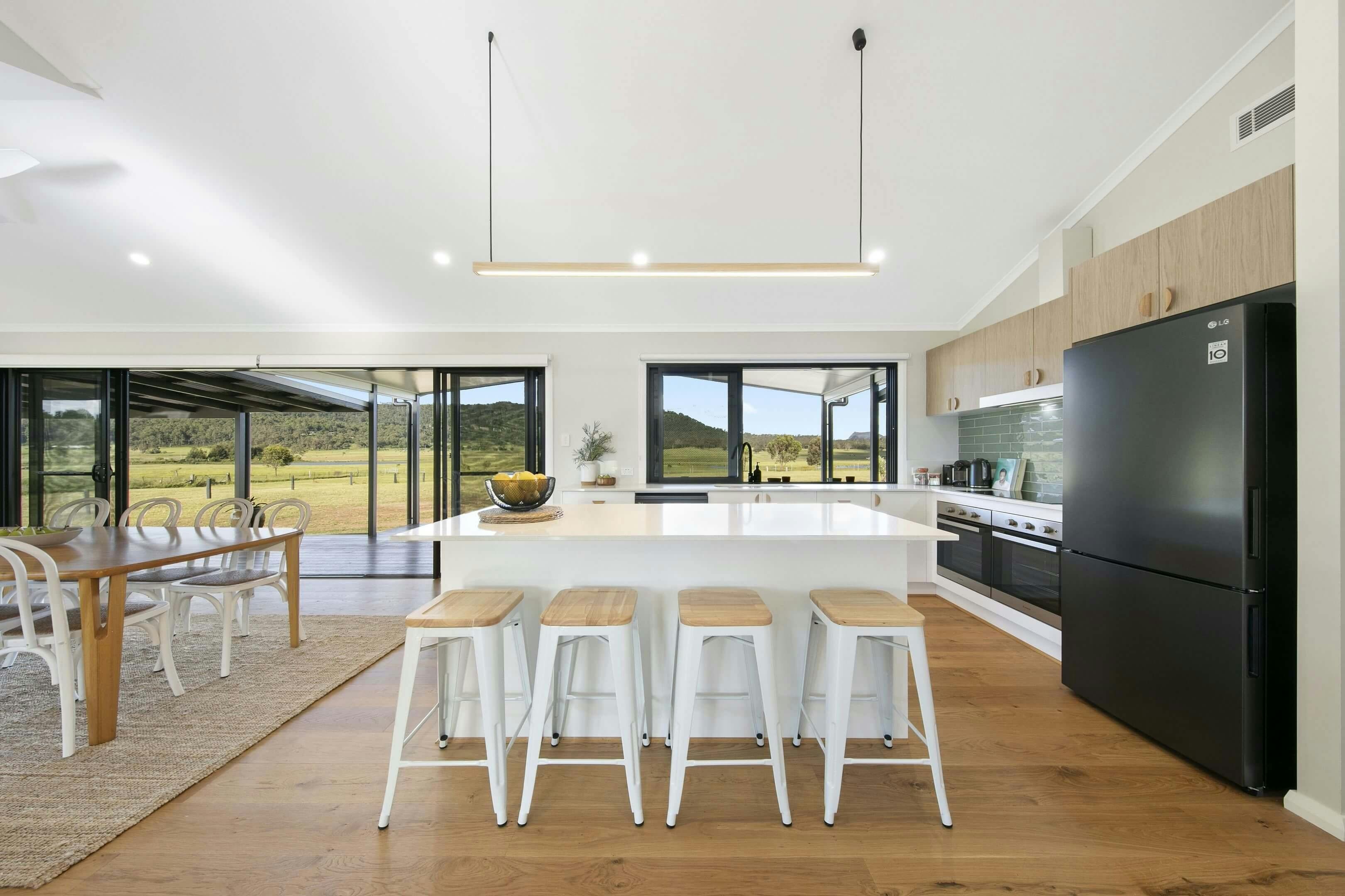 Modern open-plan kitchen and dining area with island, bar stools,  natural ight and spectacular view