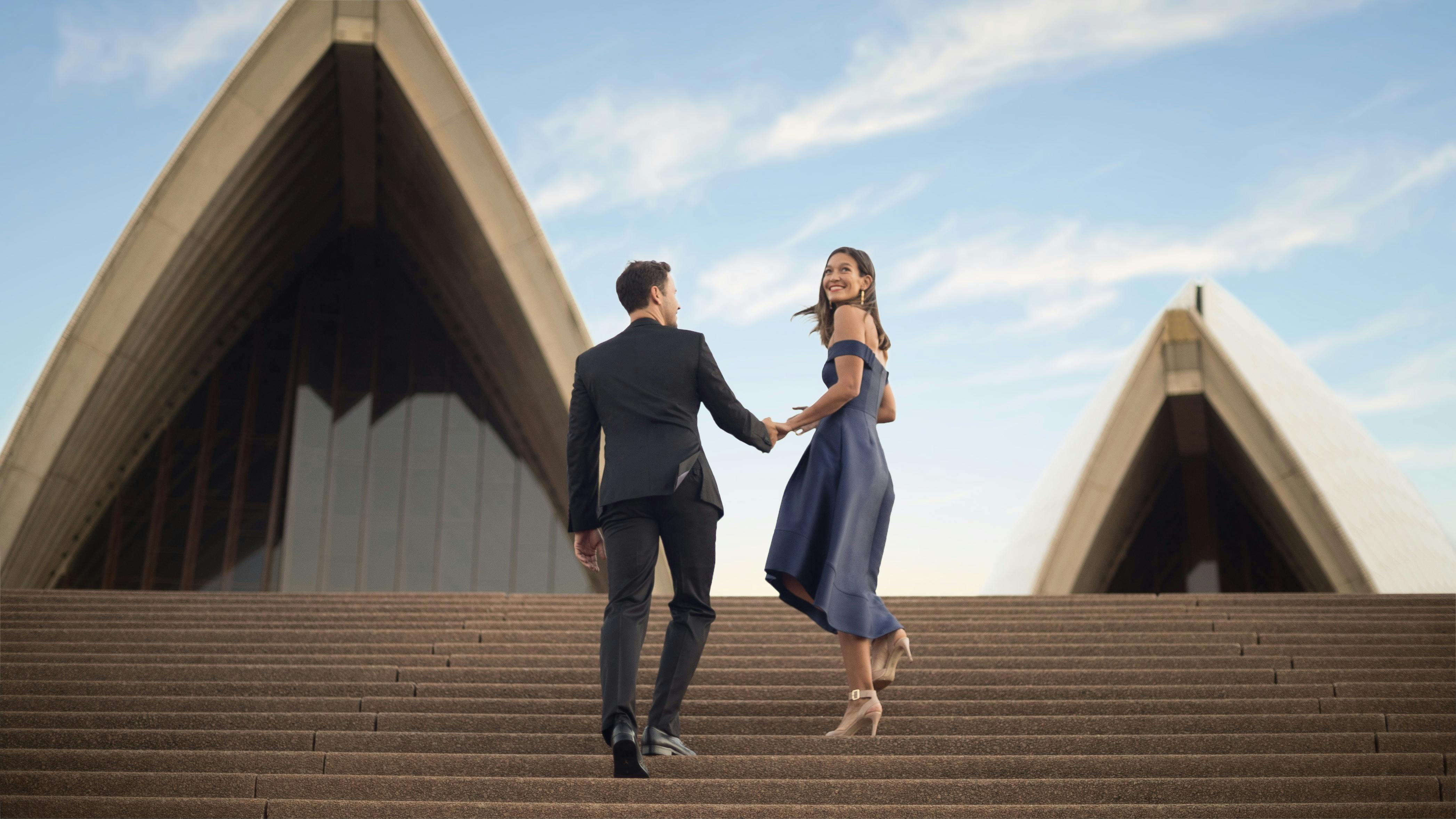 A couple climbs the steps of the Sydney Opera House
