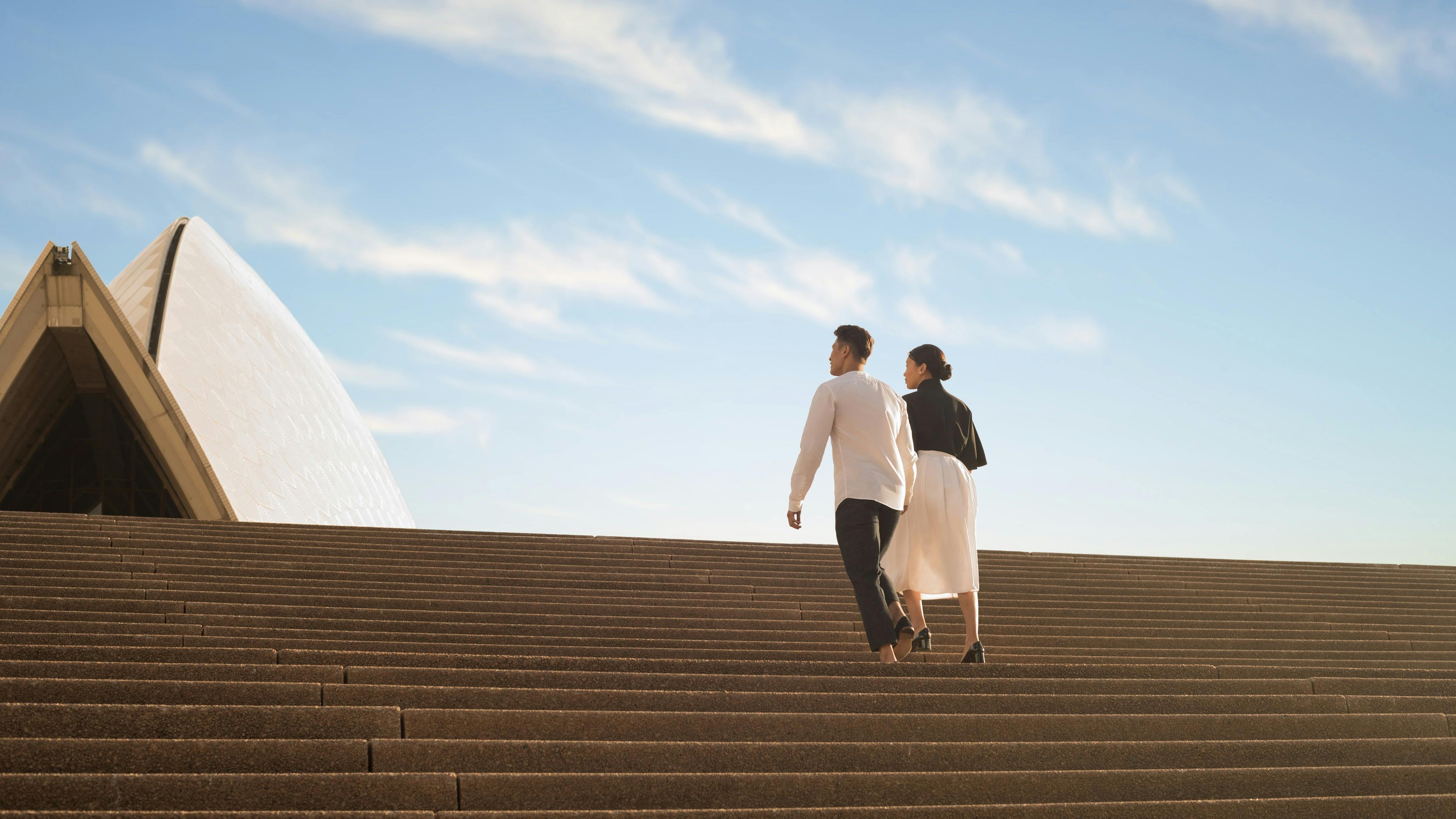 A couple climbs the steps of the Sydney Opera House