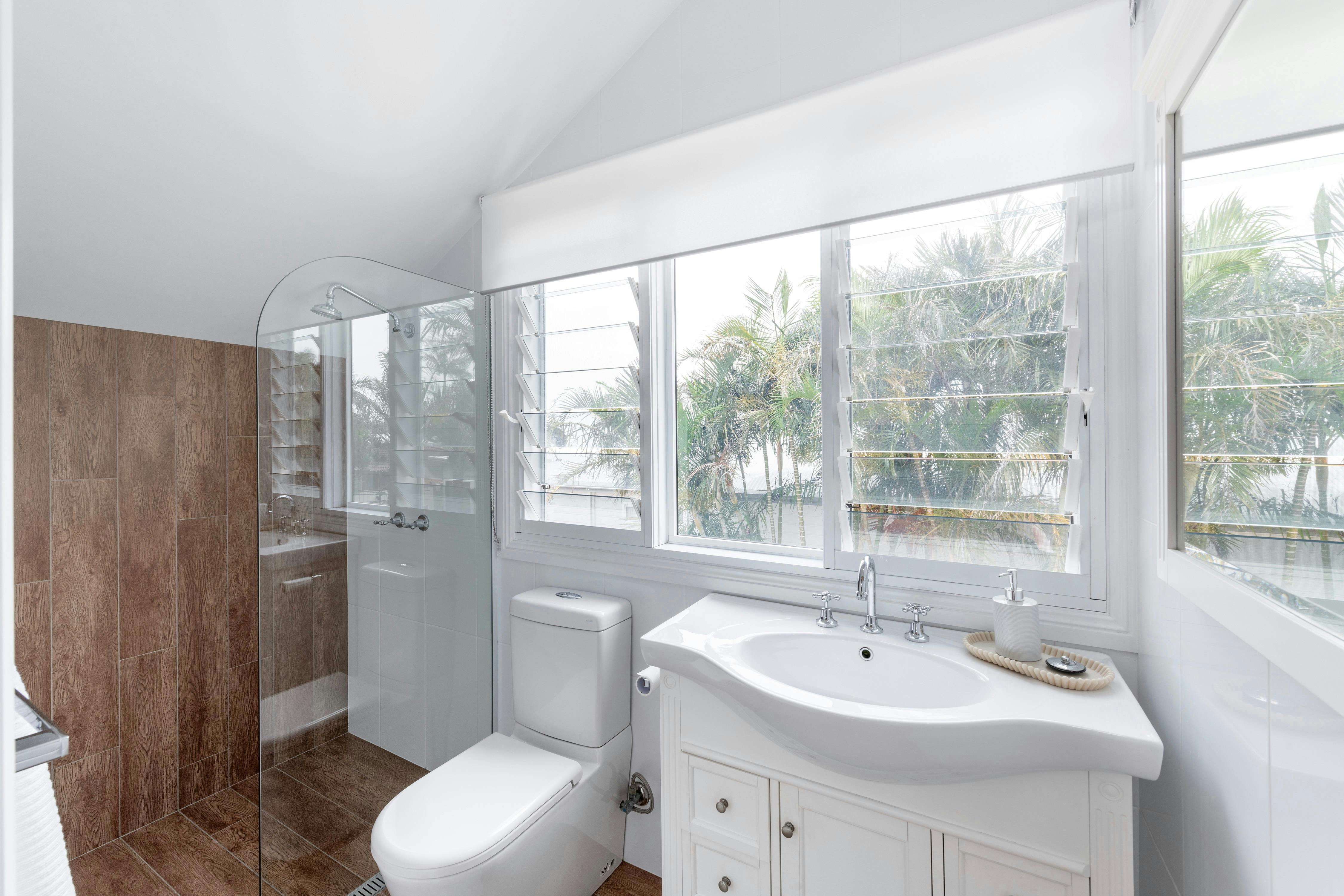 Lovely modern bathroom with frameless glass shower and private outlook over palm trees