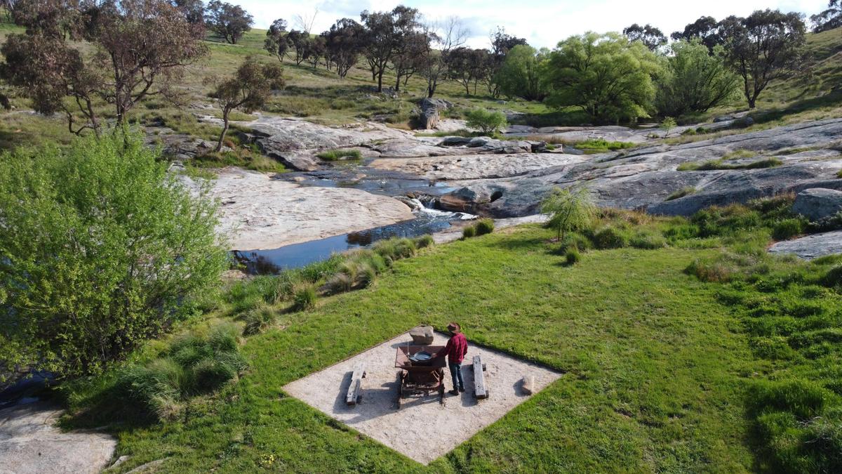 BBQ area positioned along willow treed granite creek