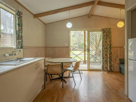 Inside one of the Wombeyan Caves cabins, showing the kitchen, dining table and open sliding glass