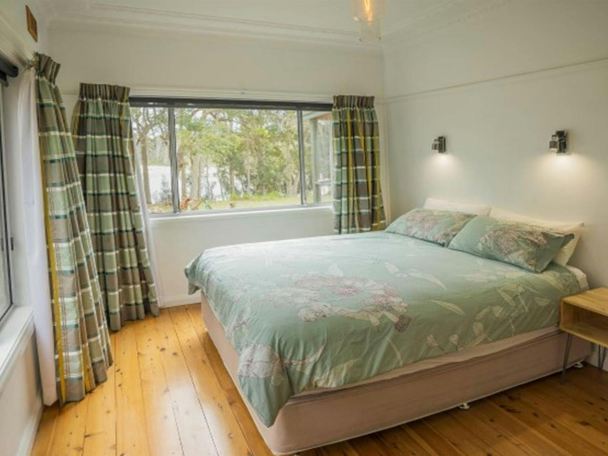 A bedroom with views out to the surrounding bush at Yellow Rock Beach House in Murramarang National
