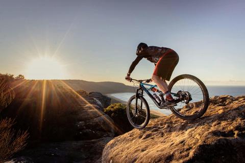 Mountain biker on dramatic rock at sunrise