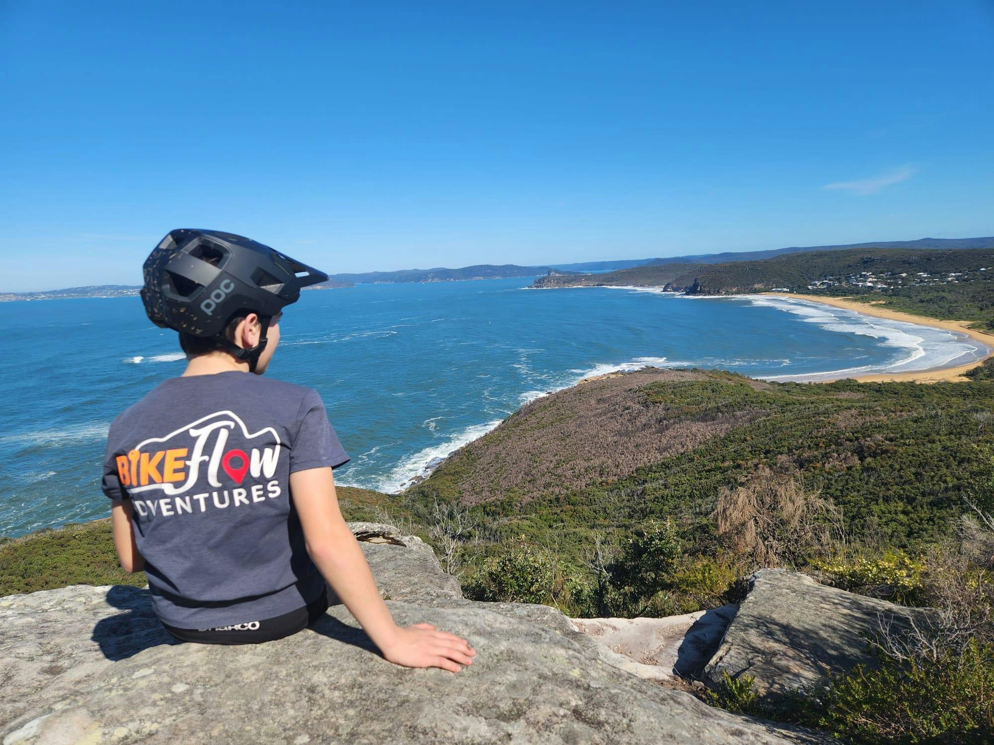 Young mountain biker overlooking dramatic beach coastline