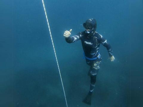 A person with a snorkel and flippers under the water diving deep