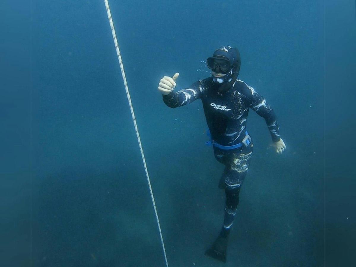A person with a snorkel and flippers under the water diving deep