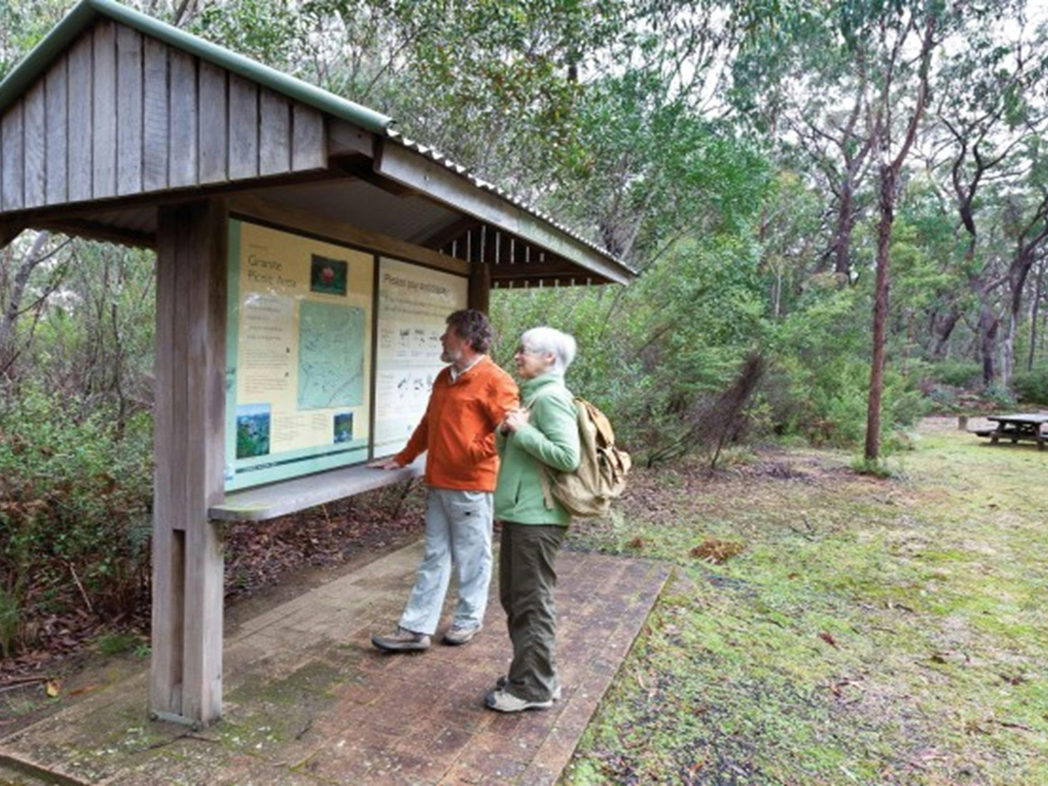 Two people looking at the interpretive signs at Granite picnic area in Washpool National Park.