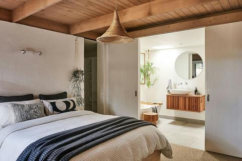 Bedroom with blue blankets and bathroom in the background.
