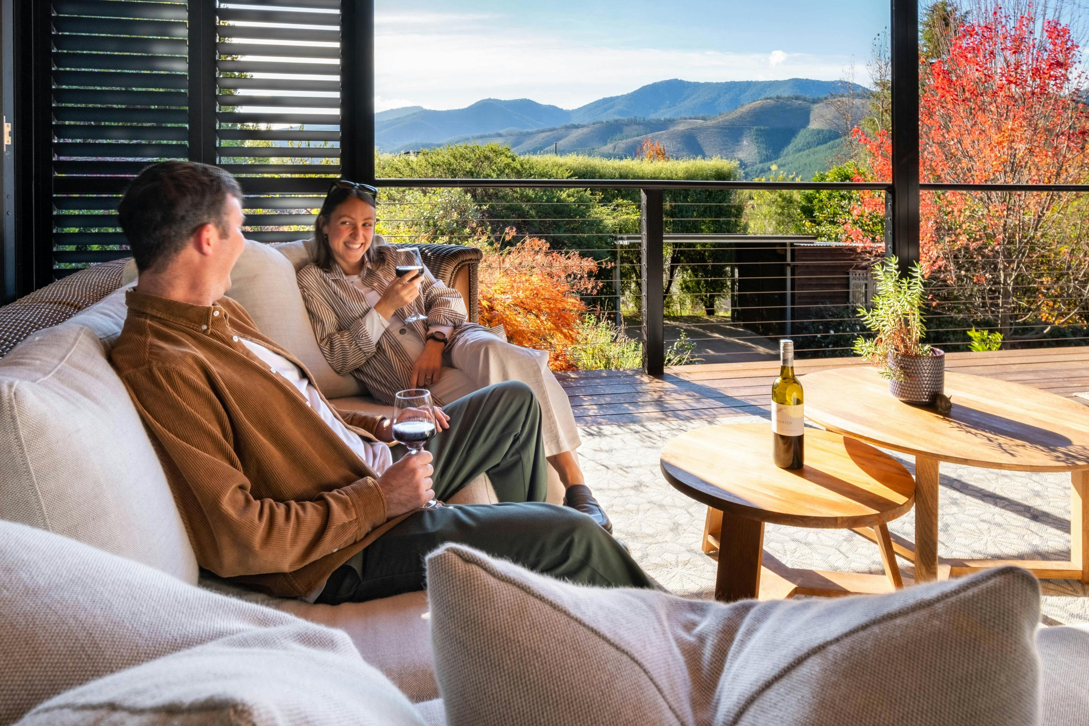 a man and woman sitting on a couch with a view of the mountains in the background