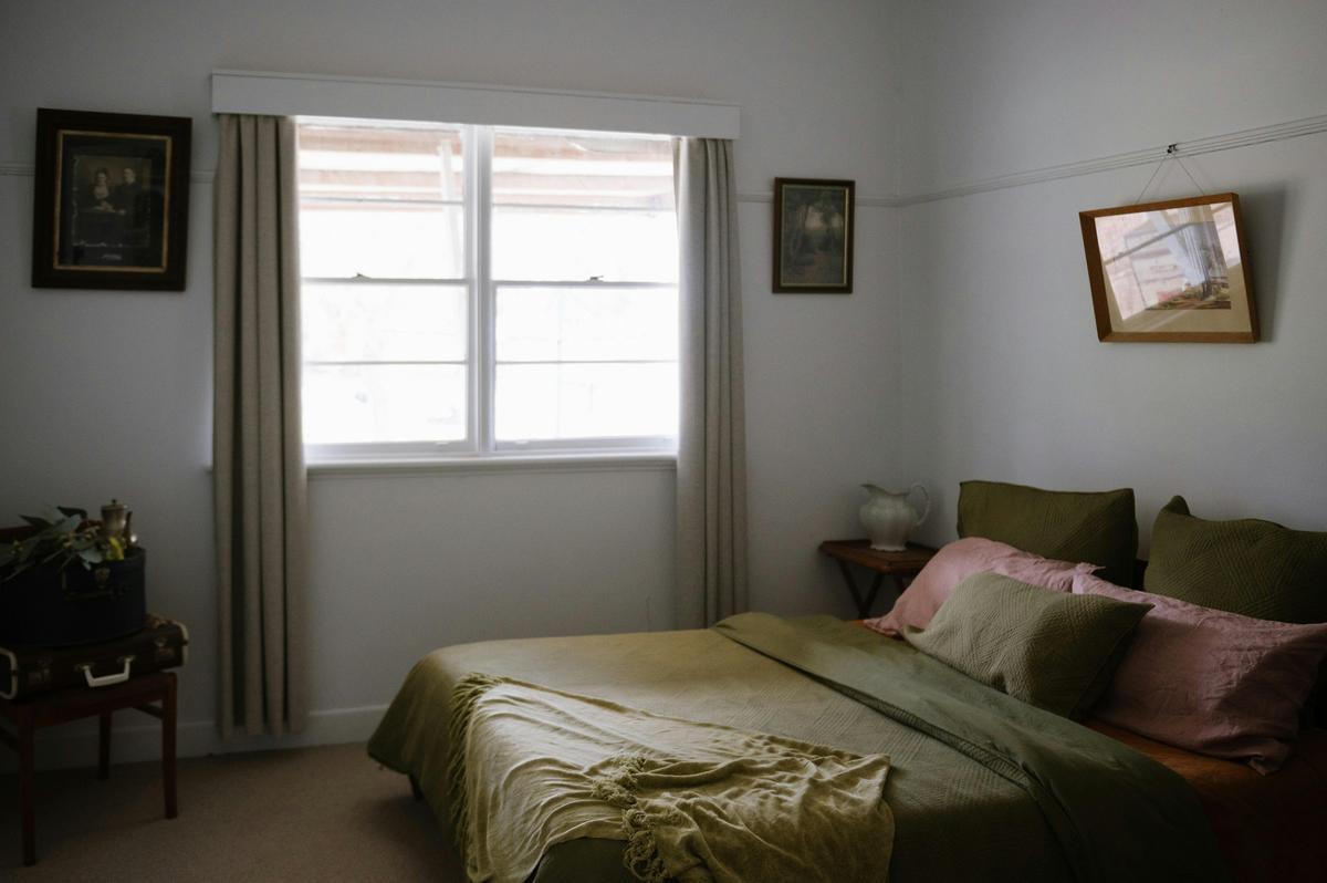 double bed inside a room with windows and picture frames on walls
