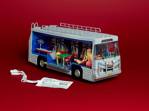 Priscilla Bus with tag in a red background.