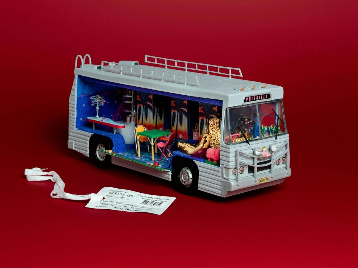 Priscilla Bus with tag in a red background.