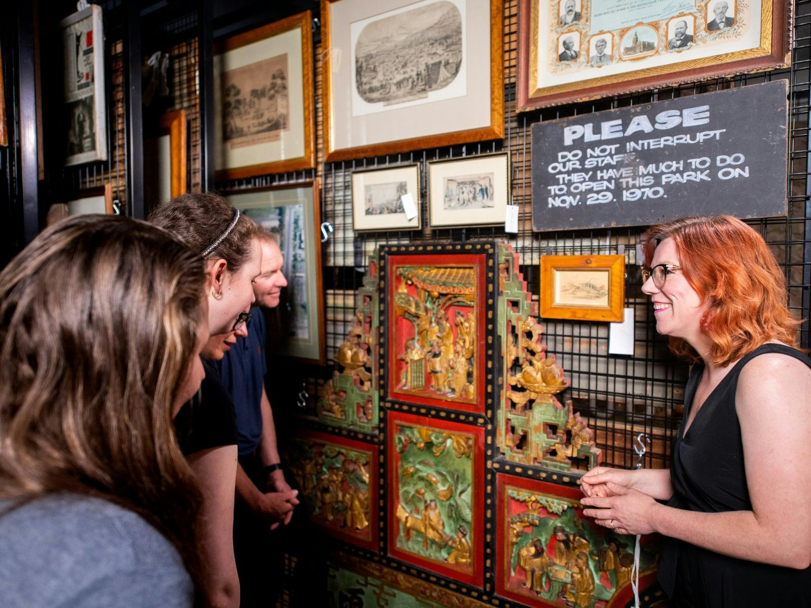 Curator showing historical Chinese temple panel to tour group