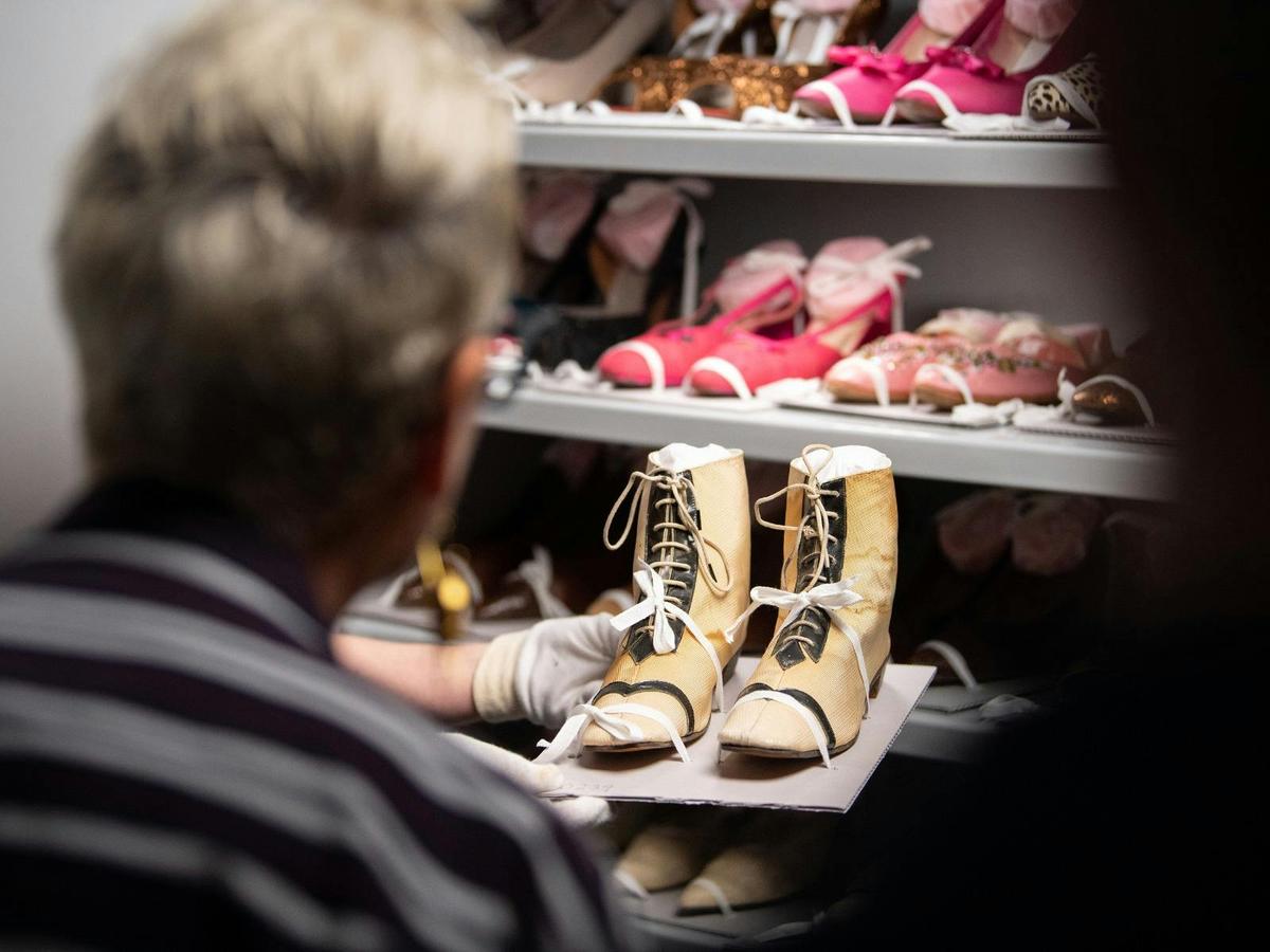 Woman closely inspecting a pair of female historical boots