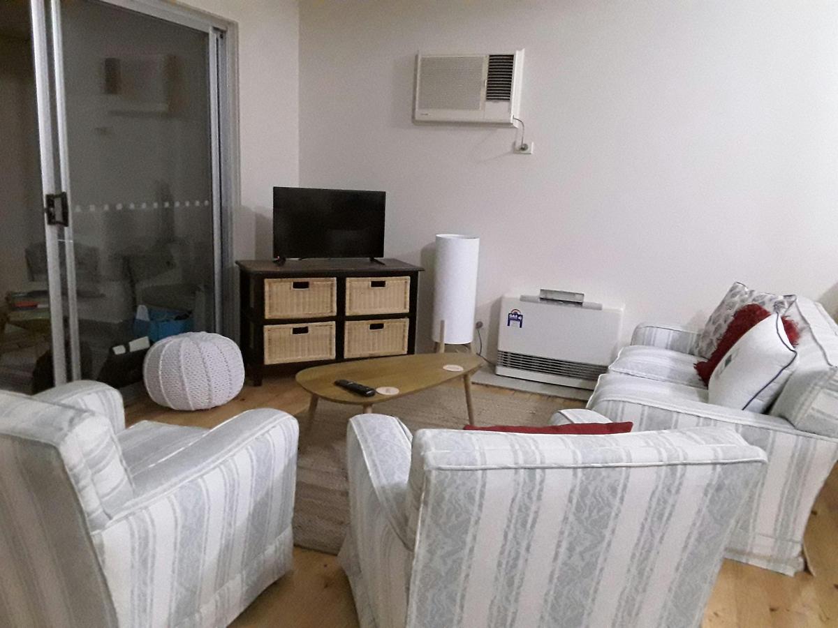 Living room has two chairs and a two seater couch. Television with dvd player