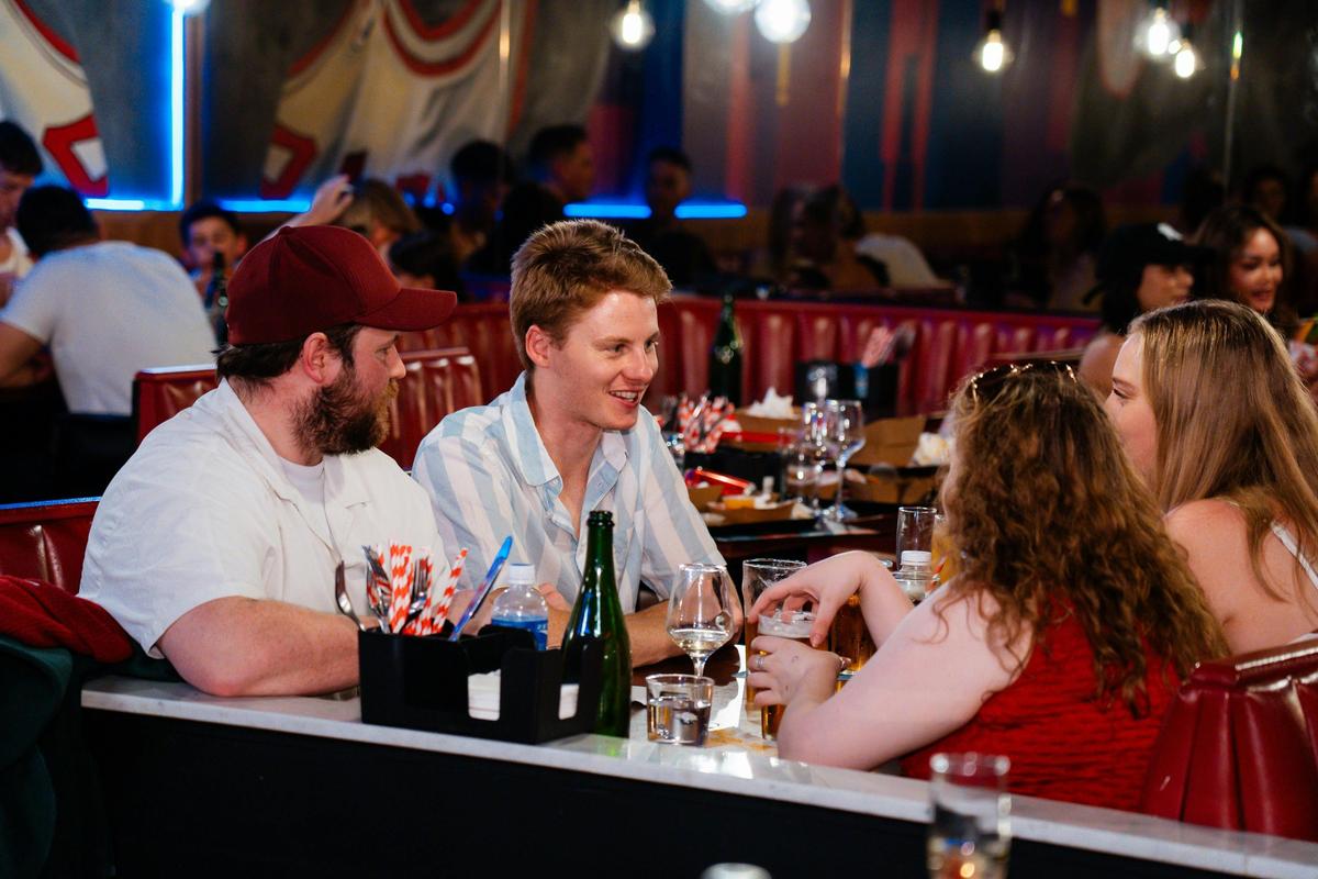 four customers sitting in a booth enjoying drinks