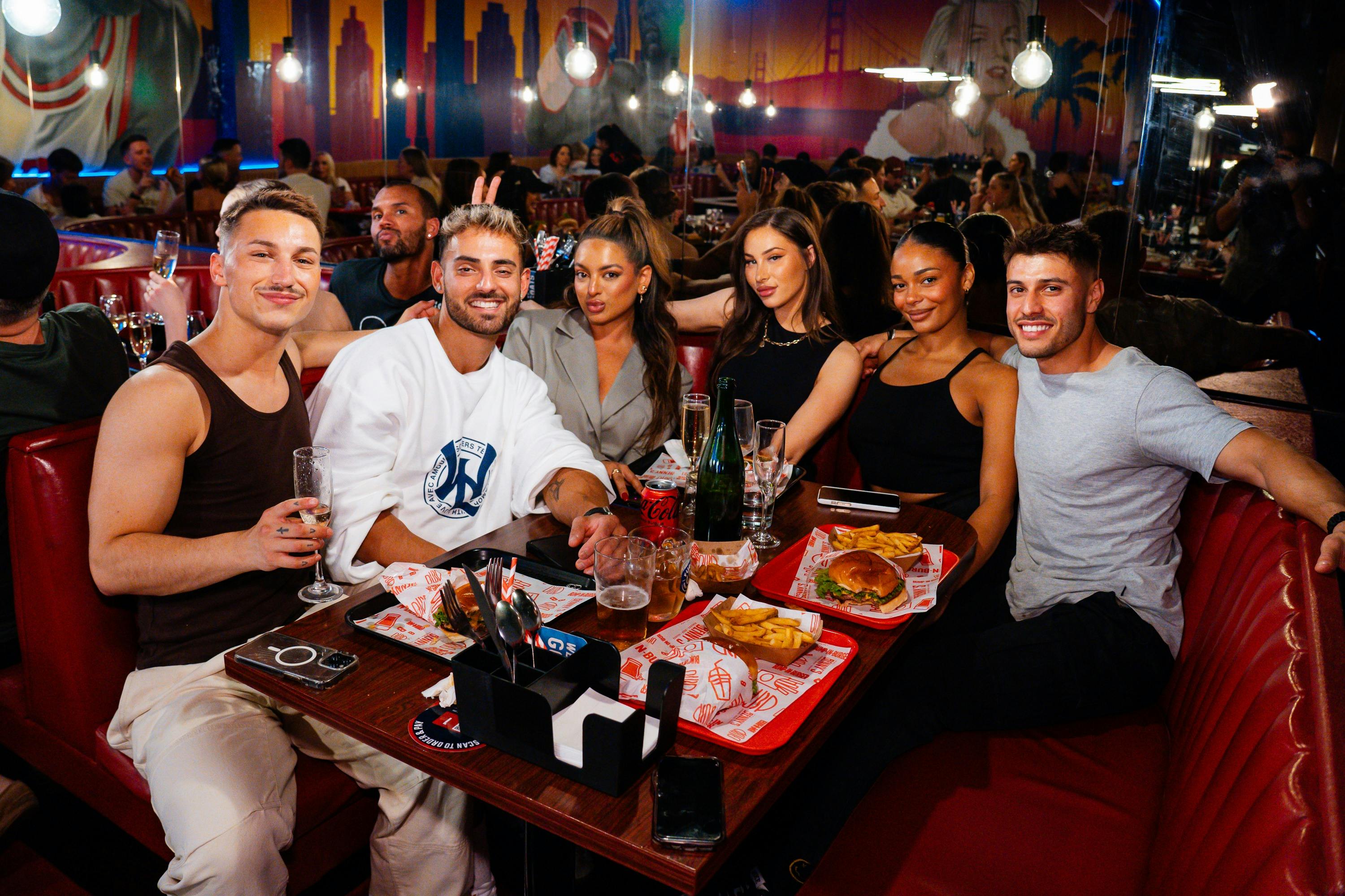 group of people seated in a booth and enjoying food and drinks