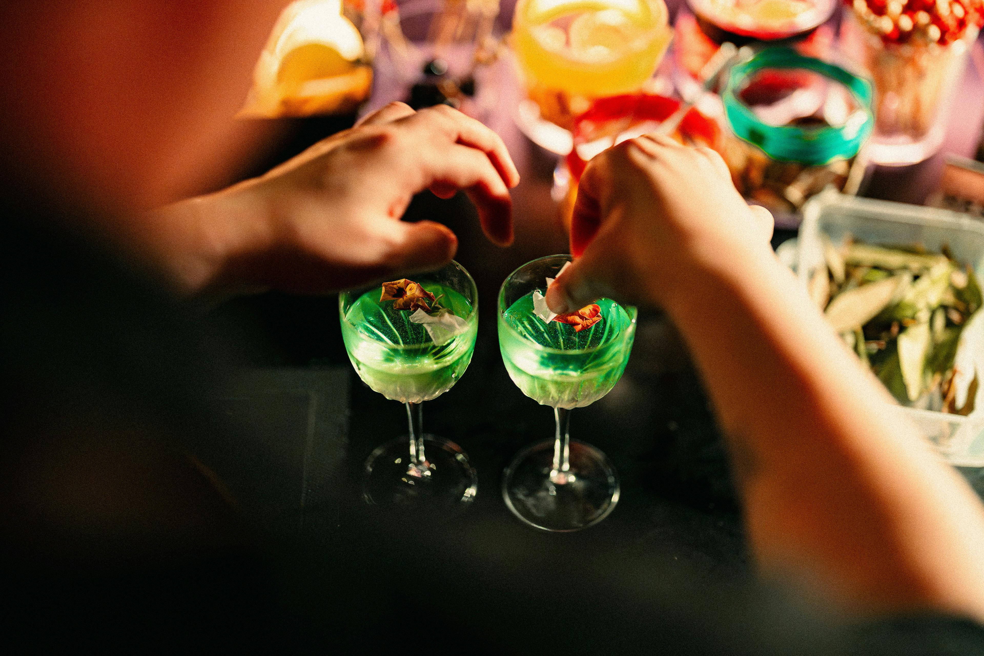 A bartender garnishes colourful cocktails.
