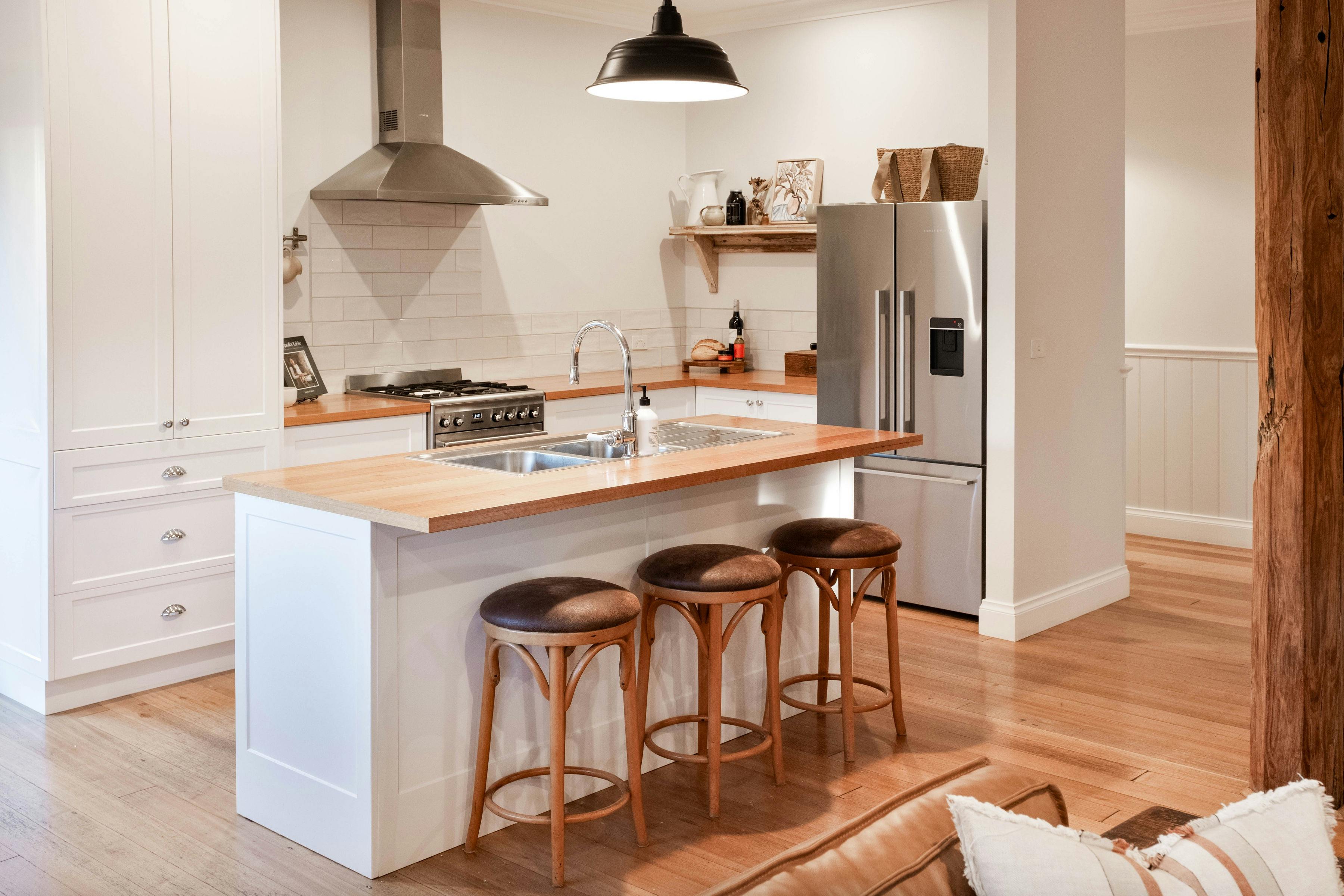 Corner Cottage Bright kitchen with a sink, refrigerator, dining area and bar stools