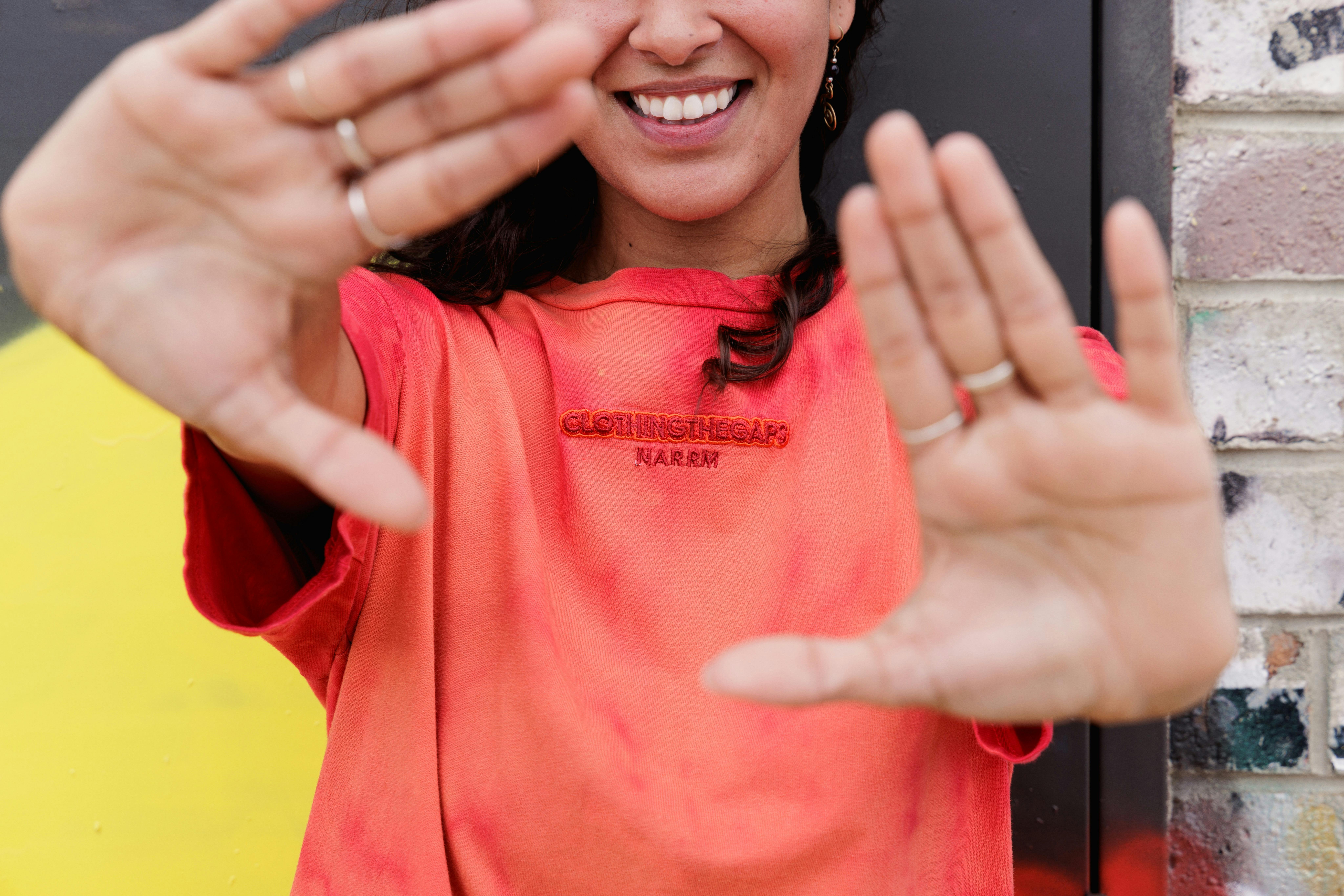 a person wearing a red top and holding their hands out smiling