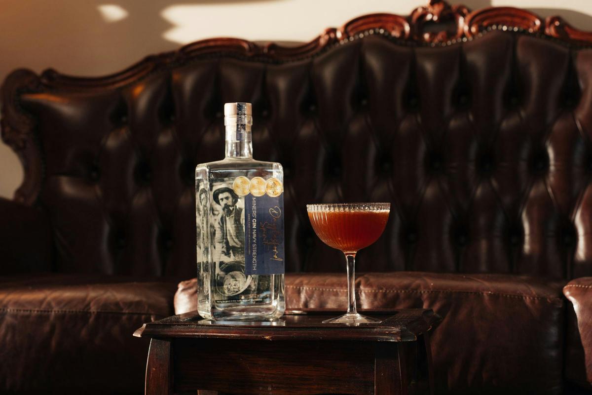 A cocktail with a bottle of Daylesford Spirit Miners Gin behind