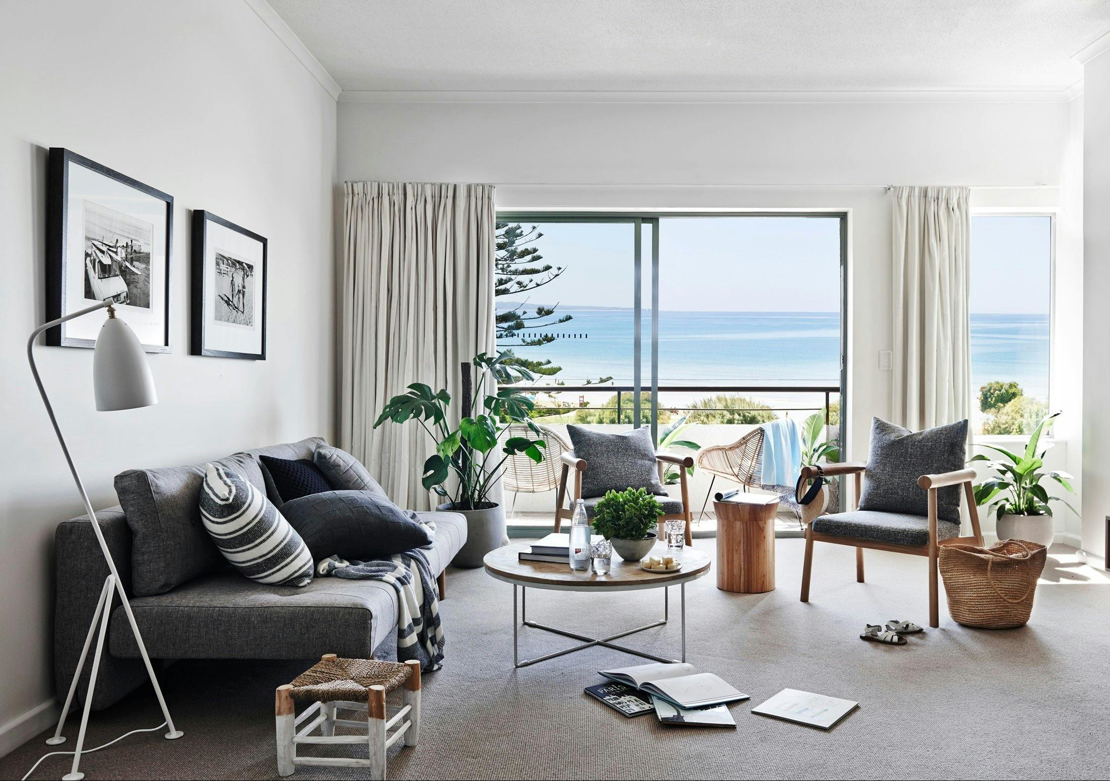 Interior of deluxe apartment lounge room with view of ocean in the background through deck window.