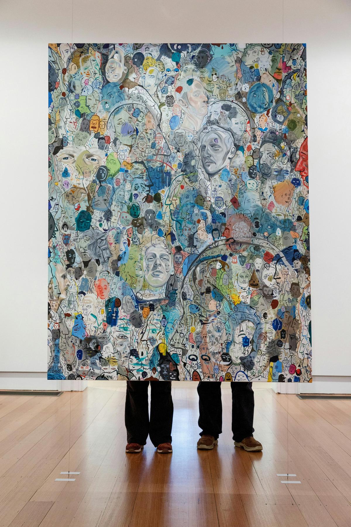 two sets of legs behind a hanging artwork at Geelong Gallery