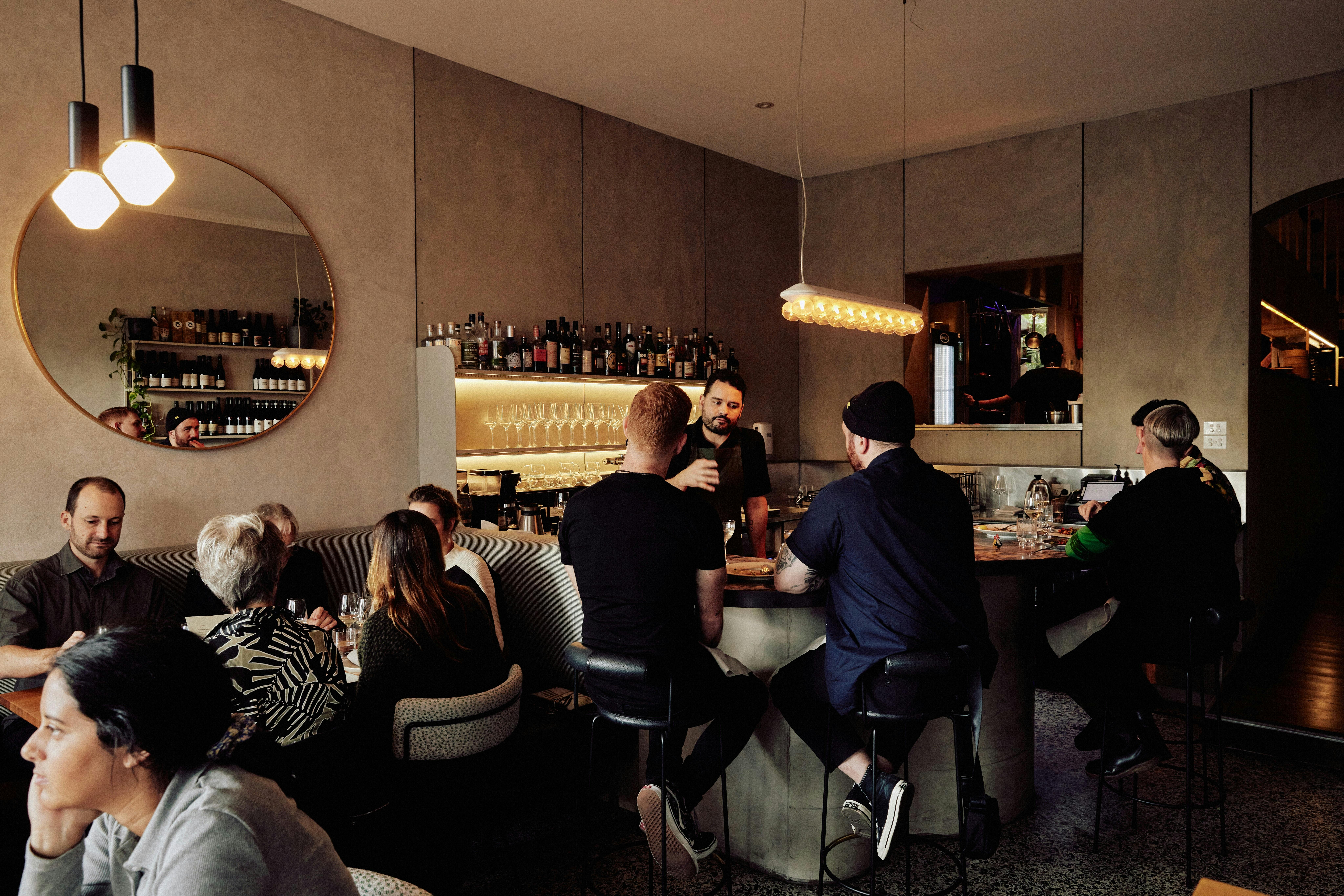 The front bar of a restaurant with a central bar and soft overhead lighting