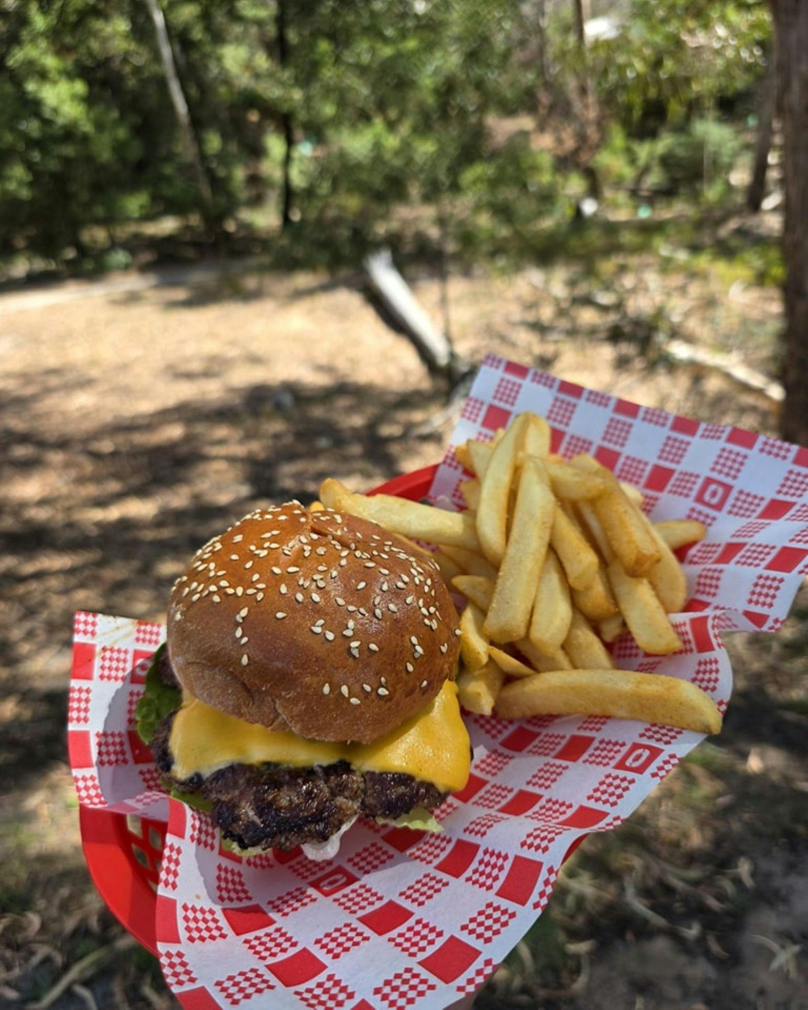 Cheeseburger and chips in a basket on an outdoor table