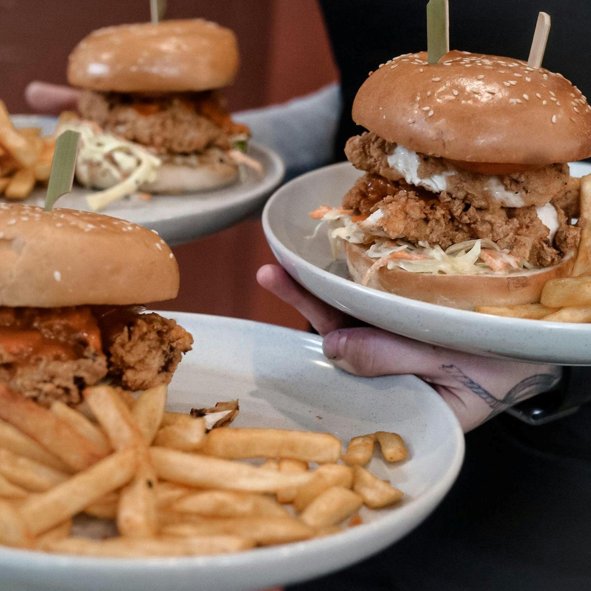 3 chicken burgers and chips on plates