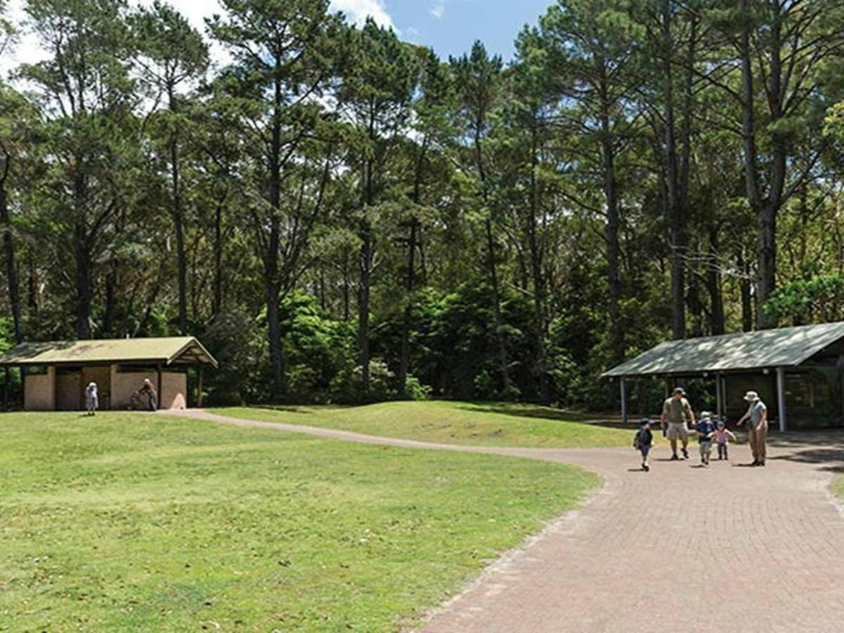 A family pass a picnic shelter at Greenfield Beach picnic area, Jervis Bay National Park. Photo: