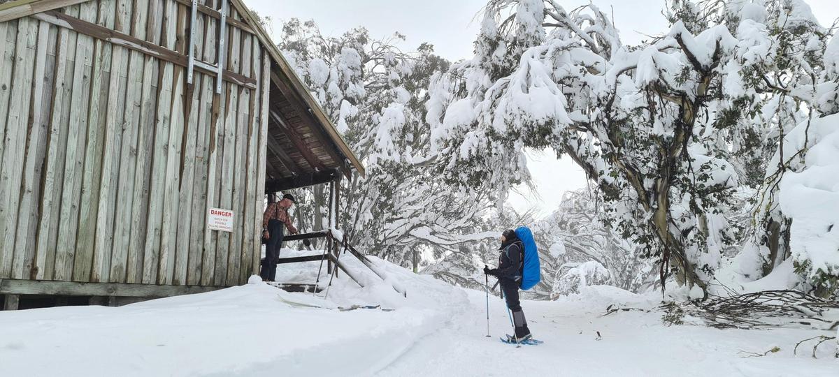 A hiker being greeted by another adventurer into the Bluff Spur Memorial Hut.
