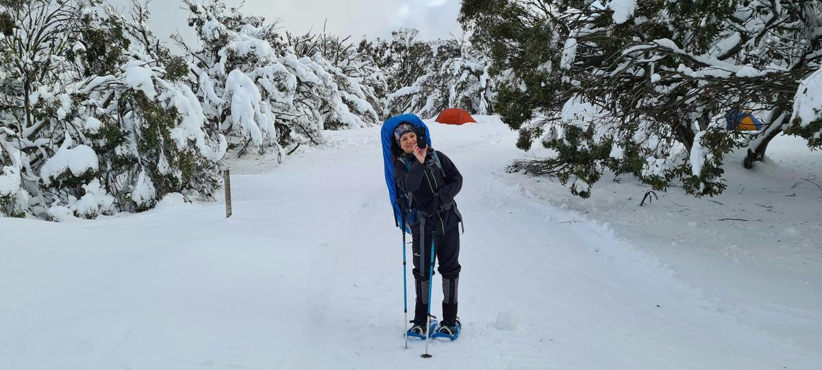 A hiker snapping photos of the snow covered landscape.