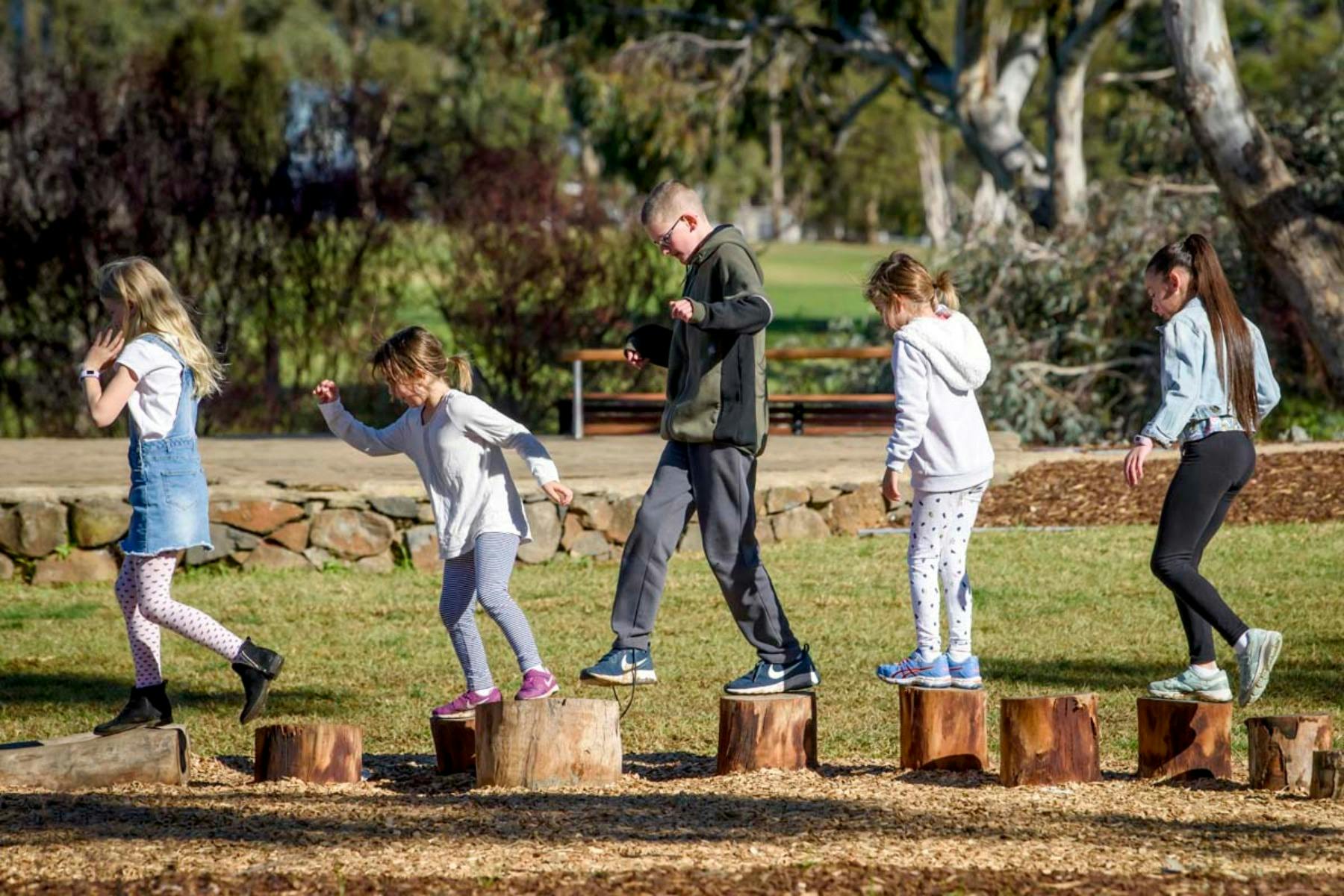 children walking across wooden logs