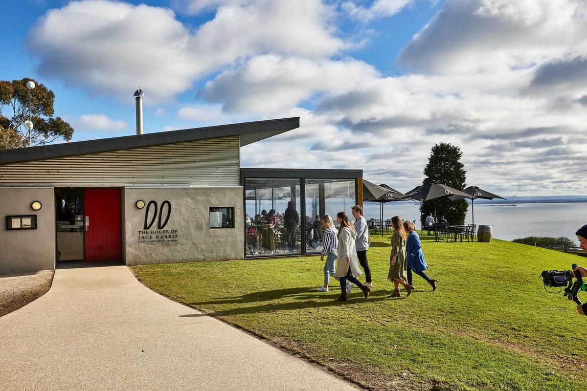 people walking towards the door of the Jack Rabbit winery with the ocean in the background