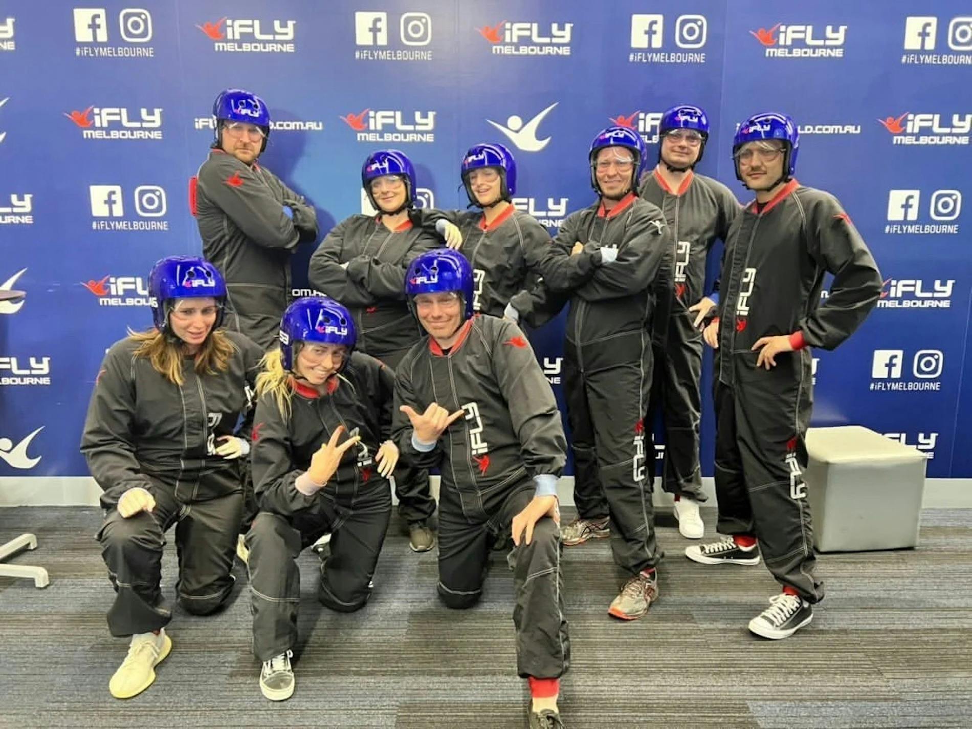 Group of visitors posing in flight suits before their indoor skydiving session.