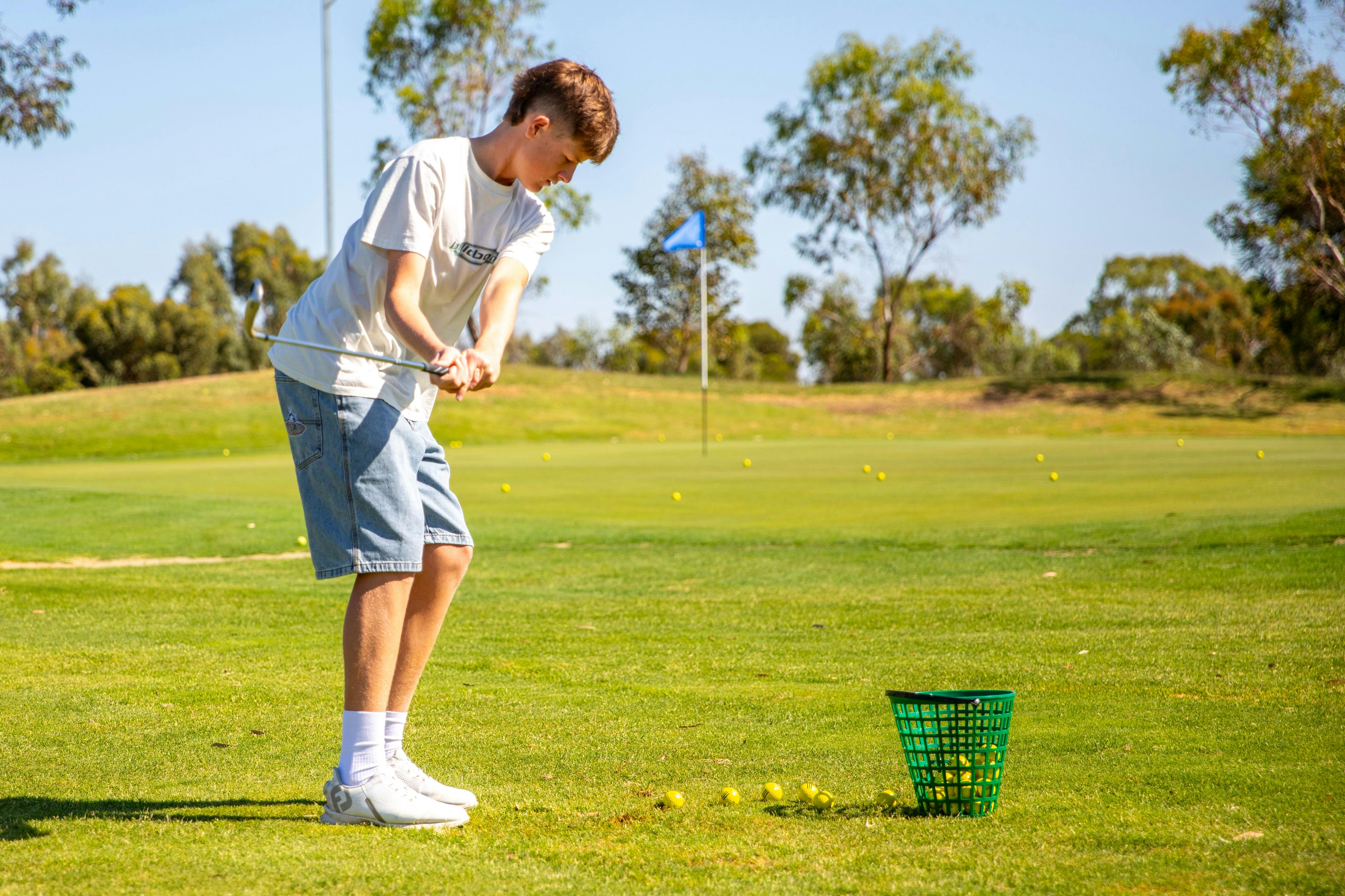 Young person practicing on a tee on a golf course